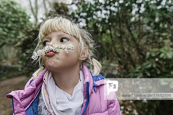 Cute girl making mustache with white flowers
