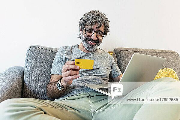 Happy man using credit card for paying financial bills at home