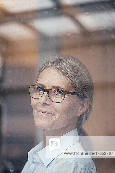 Mature woman with eyeglasses seen through glass