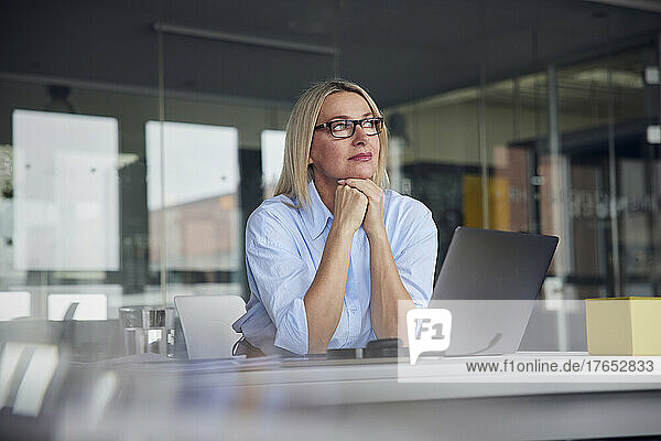 Businesswoman wearing eyeglasses with laptop at desk in office