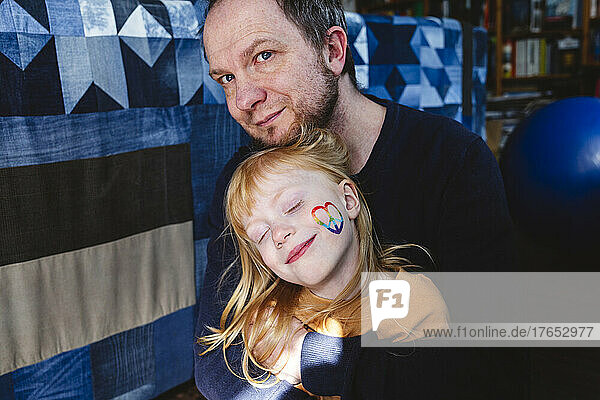 Smiling mature man with cute blond daughter at home