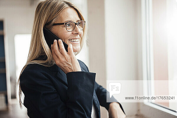Smiling businesswoman talking on mobile phone in office