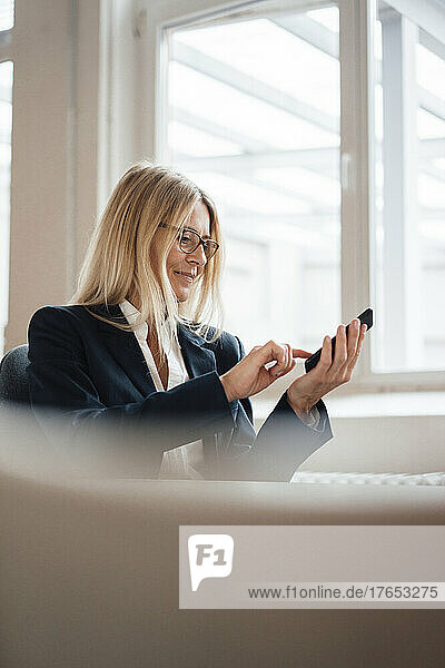 Businesswoman text messaging on smart phone in office