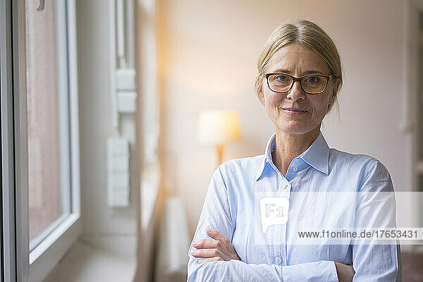 Confident businesswoman with arms crossed at work place