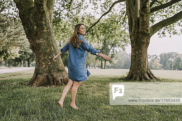 Happy woman with arms outstretched spinning in park