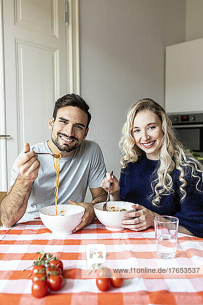 Boyfriend and girlfriend having noodle on dining table at home