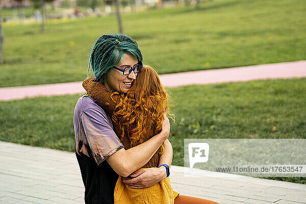 Smiling mother hugging daughter in public park