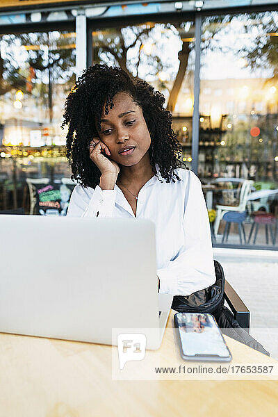 Nachdenkliche Geschäftsfrau mit Laptop sitzt im Straßencafé
