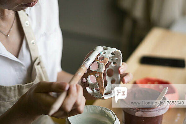 Woman painting ceramic bowl in workshop