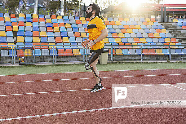 Athlete with prosthetic leg running on sports track