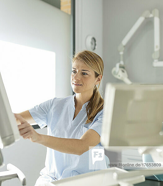 Smiling blond dentist working at dental clinic