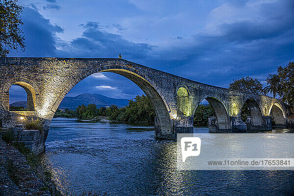 Illuminated Bridge of Arta over Arachthos river at night in Greece