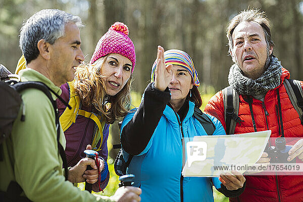 Woman with map guiding friends in forest