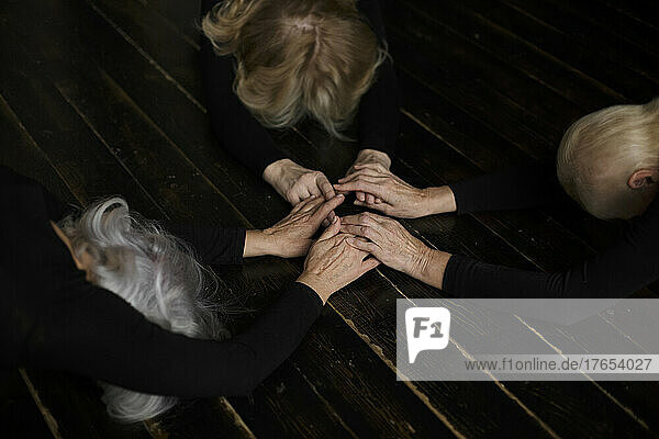 Women holding hands bowing on floor at home
