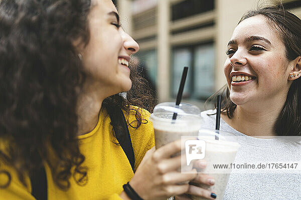 Happy friends toasting disposable milkshake cups