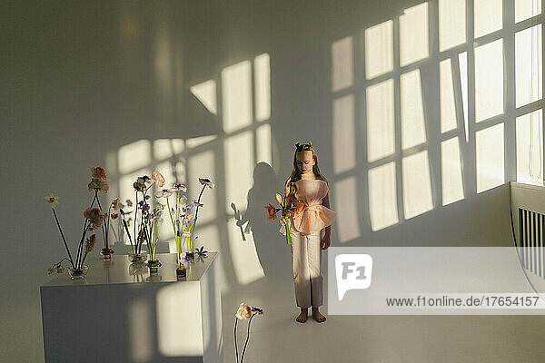 Girl with flower standing in front of white wall