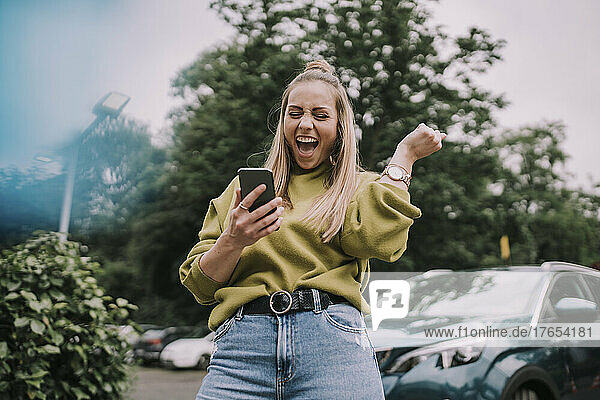 Excited young woman using smart phone