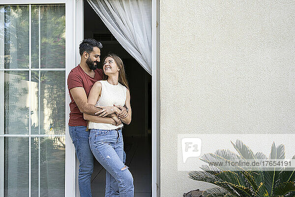 Glückliches Paar  das einander ansieht  während es an der Tür steht