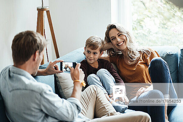 Mann fotografiert Sohn und fröhliche Frau zu Hause per Handy