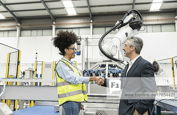 Smiling businessman shaking hand with engineer in factory