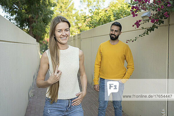 Smiling woman with long hair by man standing on footpath
