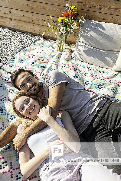 Paar umarmt sich und liegt auf der Picknickdecke auf der Terrasse