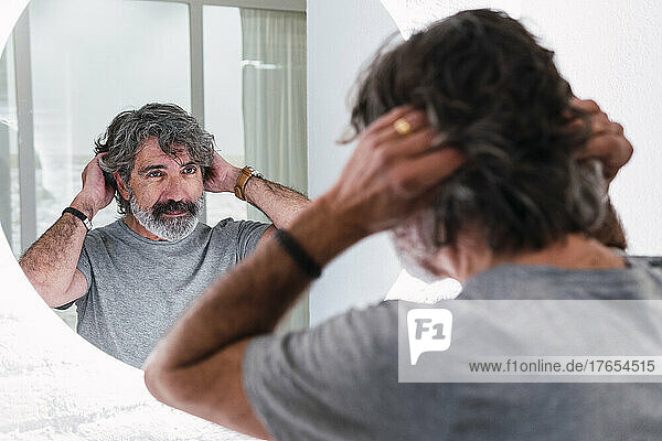 Senior man with head in hair looking at mirror