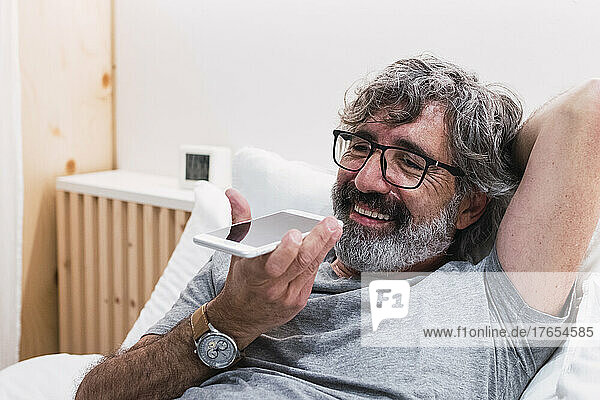 Happy man with eyeglasses talking on mobile phone at home