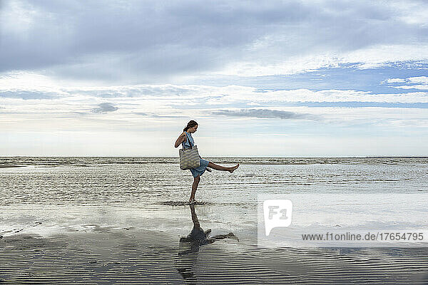 Girl with bag playing in water at beach