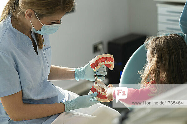 Dentist teaching daughter oral hygiene at dental clinic