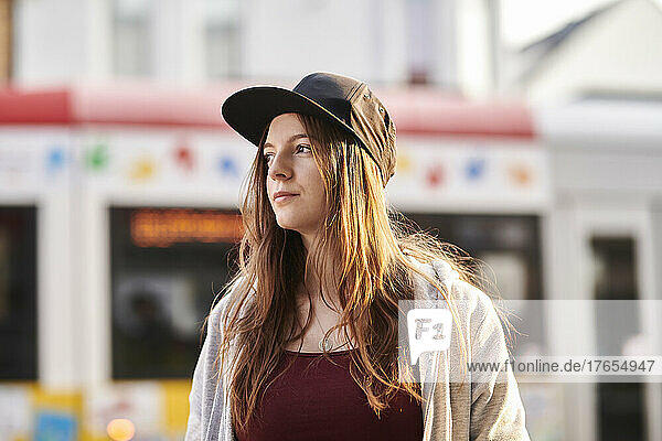 young woman with baseball cap standing in the city