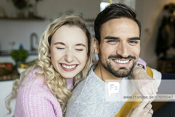 Happy girlfriend with arm around boyfriend at home