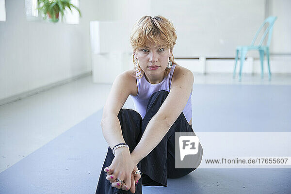 Young woman with hands clasped sitting on floor