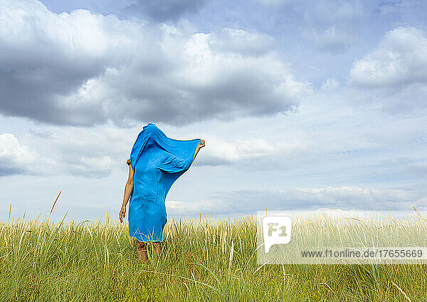 Frau mit blauem Schal bedeckt steht auf der Wiese