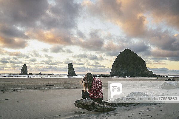 Female sitting on the beach at sunset on the Oregon Coast