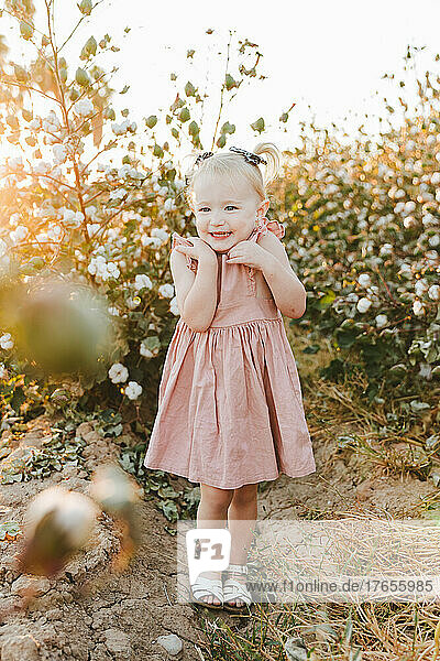 little girl smiling in front of flowers