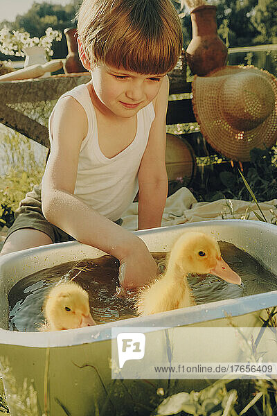 Cute boy bath outdoors in summer with ducks