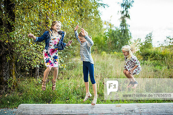 Three beautiful young girls jumping  playing outdoors.