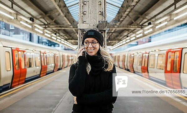 woman on a platform talking on her phone waiting for a London train