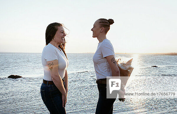 lesbian couple giving a bouquet of flowers at the beach