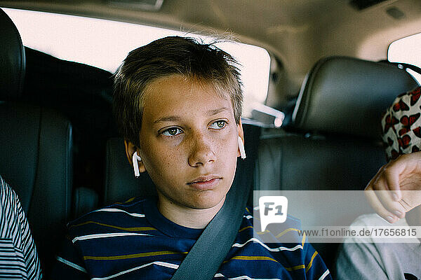 Bored Teen Boy Stuck in Backseat with Earphones on a Roadtrip