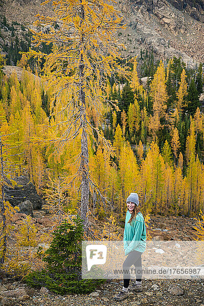 Confident woman in a forest of larches in the mountains