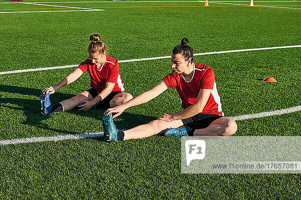 Two female soccer players stretch during a training session
