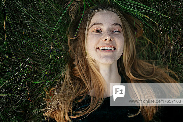Happy woman lying on the grass smiling