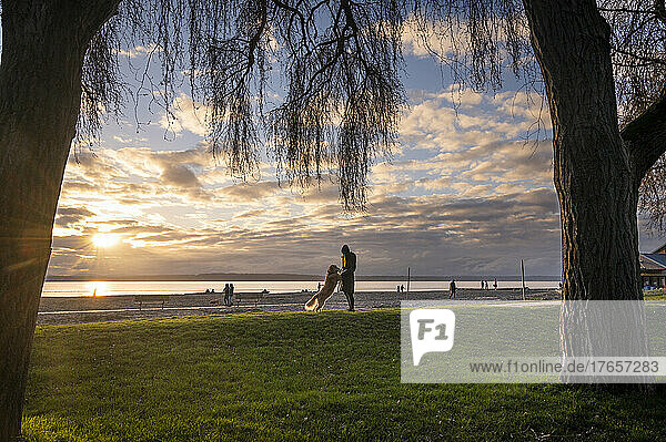 Female walking their dog in the park at sunset