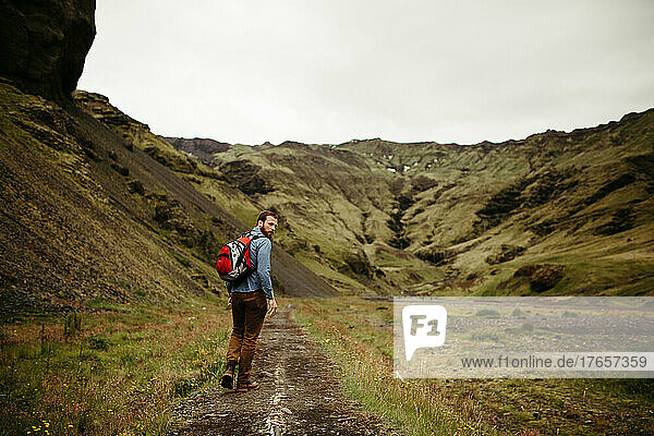 A Man Hiking in a Green Valley in Iceland