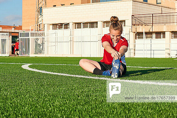 A woman soccer player stretches during a training session