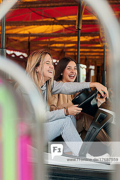 Two young women having fun while they are driving a bumper car
