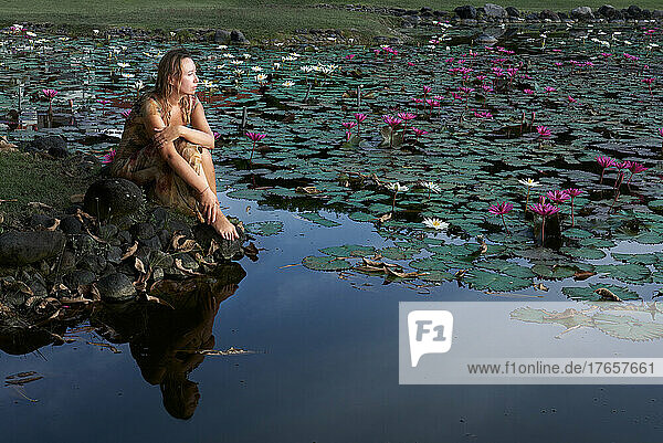 woman sitting on the lake with lotuses