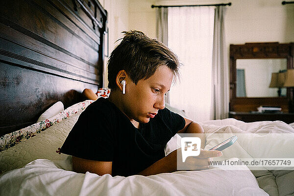 Teen Boy With Headphones and iPhone on Antique Bed